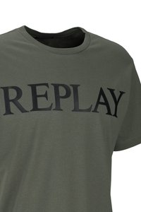 Olivgrünes T-Shirt mit Rundhalsausschnitt und kurzen Ärmeln, mit schwarzem, großem Aufdruck "REPLAY" auf der Brust.