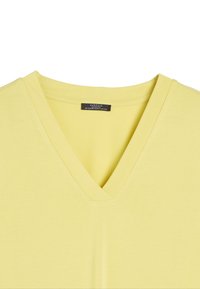 Żółta koszulka z dekoltem w kształcie litery V, wykonana z miękkiej bawełny, o gładkiej teksturze i prostym kroju bez wzorów czy zdobień.