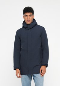 Giacca impermeabile di colore blu navy con colletto alto e cappuccio. Presenta una chiusura con zip, tasche laterali e una texture liscia.