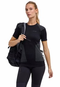 Czarny sportowy T-shirt z teksturowanymi szarymi akcentami. Posiada krótkie rękawy i dopasowany krój, zestawiony z czarnym plecakiem na paskach.