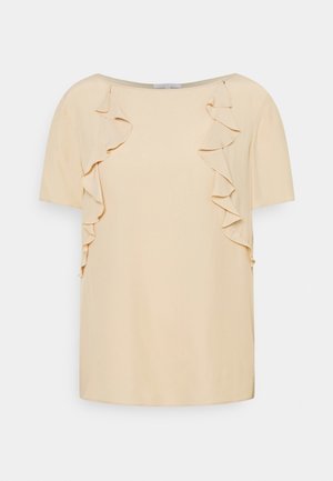 Roomkleurige korte mouwen blouse met boothals en verticale ruches aan de voorzijde, tegen een effen achtergrond.