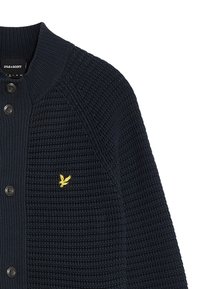 Cardigan lavorato a maglia blu navy con un design a coste, cinque bottoni neri e un piccolo logo di un'aquila gialla sul lato sinistro del petto.