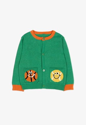 Cardigan vert en tricot avec bordure et poignets orange, présentant des visages souriants de ballons de basket et de tennis sur les poches avant.