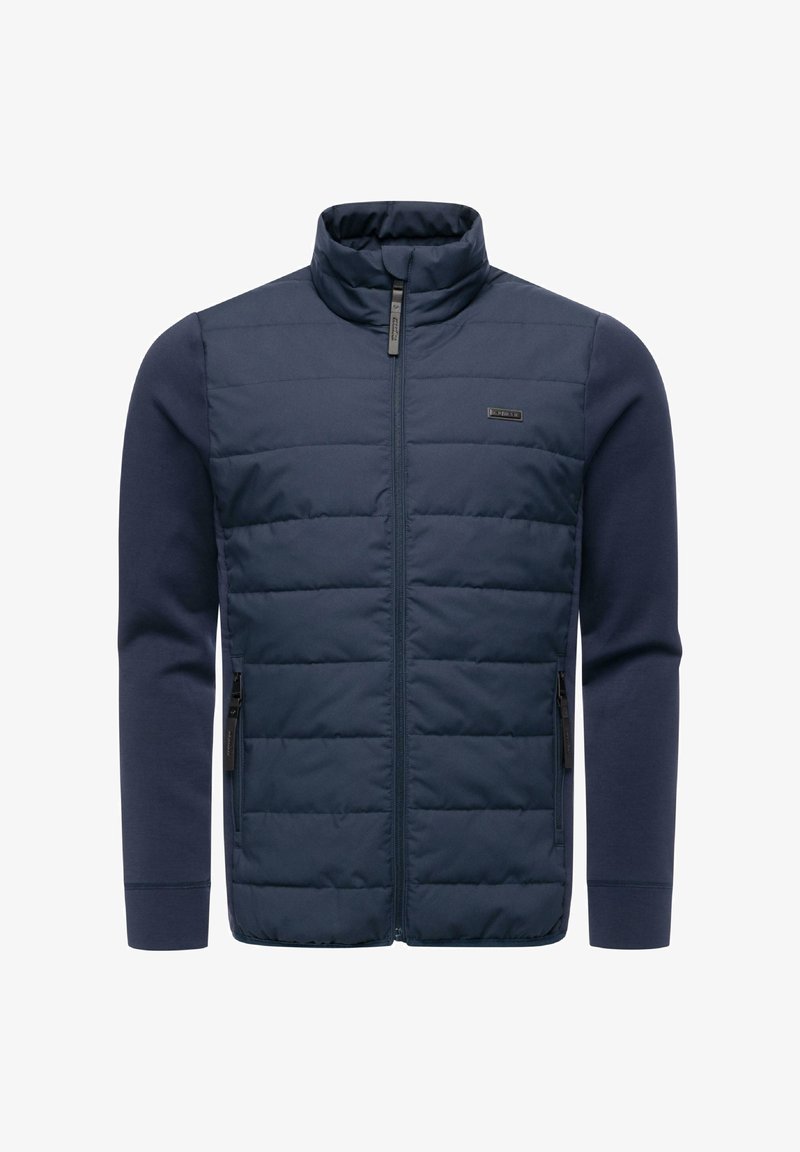 Mörkblå jacka med vadderad framdel, hög krage och långa ärmar. Har sidofickor med dragkedja och en mjuk tygstruktur.