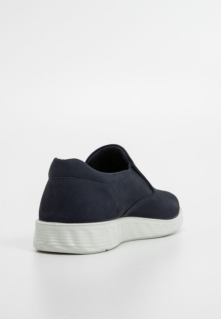 Granatowe buty slip-on z miękkim zamszowym wierzchem, zaokrąglonym tyłem i teksturowaną gumową podeszwą dla lepszej przyczepności. Minimalistyczny design bez widocznych elementów metalowych.