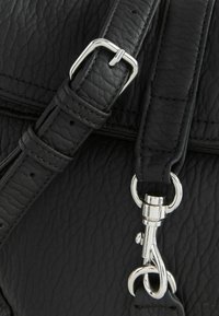 Zwarte leren handtas met een gestructureerde afwerking, voorzien van een zilveren metalen gesp en sluiting. De riem is verstelbaar met meerdere gaatjes.