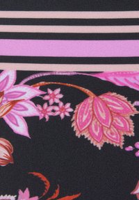 Tissu floral présentant de grandes fleurs roses et oranges sur un fond noir, avec des rayures horizontales roses et beige. Texture lisse.