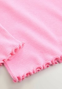 Țesătură roz cu nervuri și margine plisată. Textura este moale, iar designul are linii verticale și un detaliu ondulat la tiv.