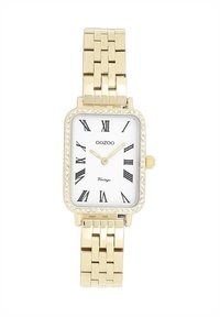 Montre rectangulaire en or avec un cadran blanc, des chiffres romains noirs, un mouvement à quartz et une lunette ornée de cristaux. Bracelet en métal à maillons.