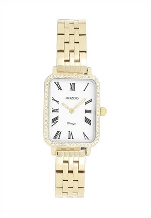 Montre rectangulaire en or avec un cadran blanc, des chiffres romains noirs, un mouvement à quartz et une lunette ornée de cristaux. Bracelet en métal à maillons.