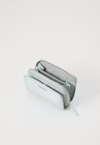 Ljust grå läderplånbok med zip-stängning, flera kortfack och en slät yta. Har en liten metall-logotyp på framsidan.
