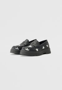 Svarta loafers med en kraftig sula, som har vita stjärnmönster på sidorna. Tillverkade av slät läder med en slip-on design.