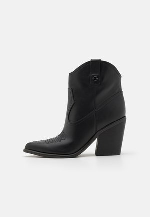 Czarne skórzane botki za kostkę z czubkiem w kształcie stożka i przeszywanym wzorem. Posiadają smukły obcas oraz pętelkę z tyłu.