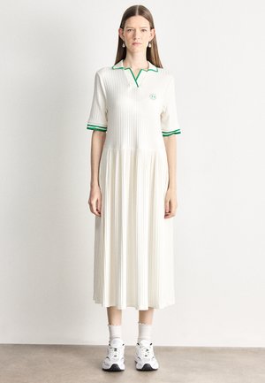 Polo dress in white with vertical ribbed texture and green accents on the collar and sleeves, featuring a fitted bodice and flared skirt.