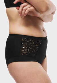 Svarta underkläder med hög midja, prydda med ett spetsinslag med blommönster och prickig struktur. Slät tyg runt kanterna.