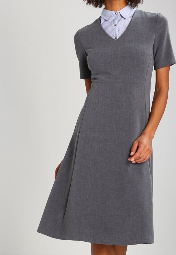 Robe grise à manches courtes avec un col en V et une chemise bleue claire à col en dessous. La jupe s'évase doucement à partir de la taille. Tissu texturé.