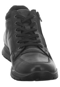 Chaussure mi-haute en cuir noir avec un bout arrondi, des lacets à l'avant et une fermeture éclair sur le côté. Elle dispose d'une semelle en caoutchouc texturé et d'un col rembourré pour le confort.