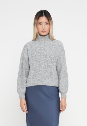 Hellgrauer, gestrickter Rollkragenpullover mit einem strukturierten Muster, ausgestattet mit überschnittenen Schultern und einem cropped Schnitt, kombiniert mit einem dunkelblauen Satinstiftrock.