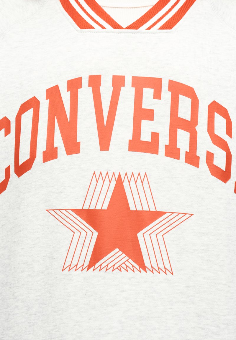 Weißer Stoff mit orange gestreiftem Kragen, großem orangenem "CONVERSE"-Schriftzug und einer mehrlagigen Stern-Grafik in der Mitte.