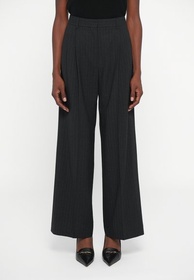 Wide-leg, charcoal gray trousers with subtle pinstripes, pleated front design, and a high waist. Styled with pointed black shoes.
