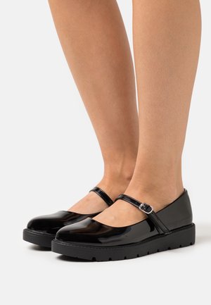 Czarne lakierowane buty Mary Jane z okrągłym noskiem, z paskiem na kostce i grubą czarną podeszwą, z małym metalowym zapięciem.