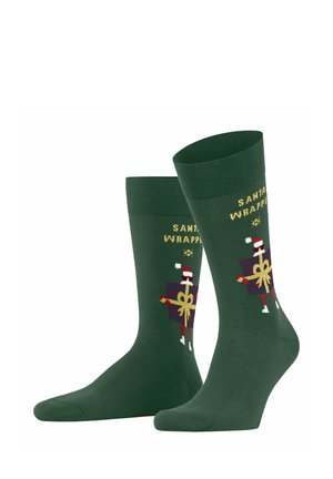 Chaussettes vertes ornées d'un design festif de papier cadeau de Noël, avec des lettres dorées et un motif de cadeau, fabriquées dans un matériau doux et extensible.