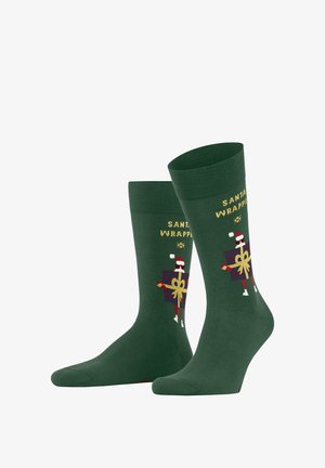 Grüne Socken mit einem festlichen Santa-Wickeldesign, goldener Schrift und einem gemusterten Geschenk, aus einem weichen, dehnbaren Material gefertigt.
