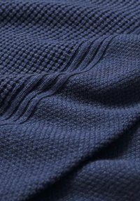 Jūras zilā austā auduma virsma ir teksturēta ar izcilām un gludām daļām, radot slāņainu izskatu. Mīksta un ar patīkamu, siltu sajūtu.