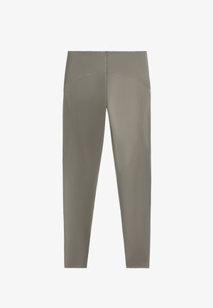 Legginsy o wysokim stanie w stonowanym beżowym kolorze, z dopasowanym krojem, bezszwową konstrukcją i zaokrąglonymi szwami wzdłuż ud.