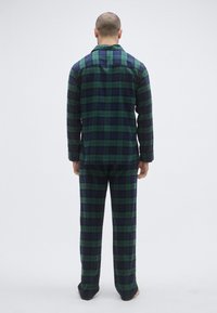 Set pidžame od flanela u tamnozelenom i mornarskoplavom kariranom uzorku. Gornji dio s dugim rukavima i ovratnikom te odgovarajuće hlače, s opuštenim krojem i mekom teksturom.