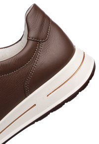 Brown leather sneaker featuring a textured upper, contrasting white sole with a gold accent, and stitched detailing. Rounded shape.