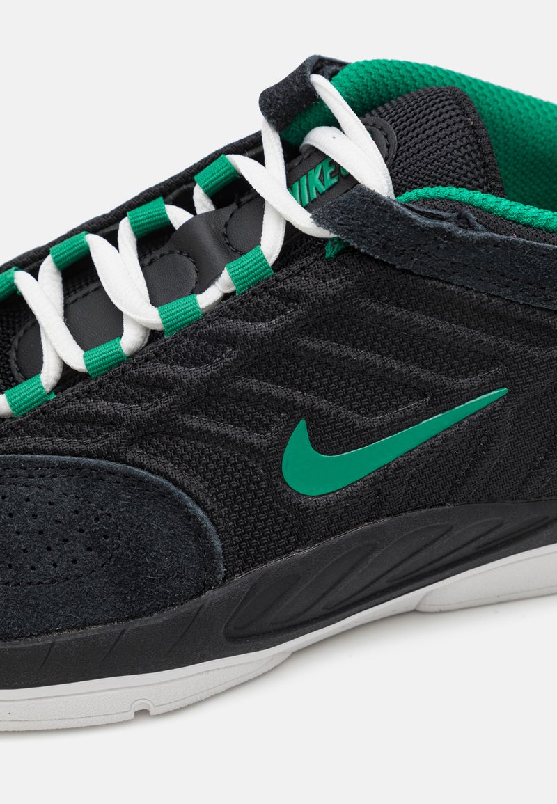 Nike-Sneaker haben ein schwarzes Mesh-Obermaterial, grüne Akzente, weiße Schnürsenkel und eine strukturierte schwarze Wildleder-Zehenspitze. Die Außensohle ist überwiegend weiß.
