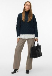 Dark teal textured knit sweater paired with a white collared shirt, beige wide-leg trousers, and a black leather handbag. Black heeled ankle boots.