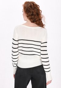 Wit en zwart gestreepte gebreide trui met een losse pasvorm en geribde manchetten, met een wijde halslijn en een zachte textuur. Gekocht met zwarte broek.