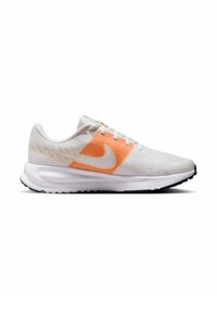 Hvide atletiske sneakers med orange accenter og en tekstureret mesh-overdel. Har en fleksibel sål og et fremtrædende logo på siden.
