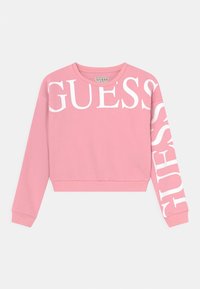 Pink sweatshirt with white "GUESS" text across the front and down the left sleeve. Made of soft material with ribbed cuffs and hem.
