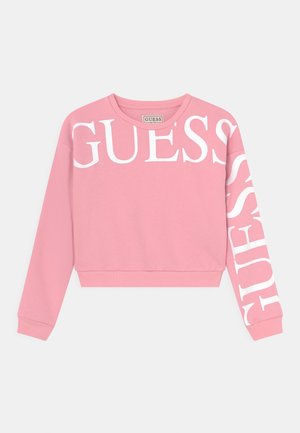 Sweatshirt rose avec le texte blanc "GUESS" sur le devant et le long de la manche gauche. Fabriqué en matériau doux avec des poignets et un ourlet côtelés.