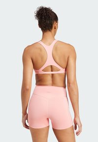 Roze naadloze sportbeha met een racerbackontwerp en uitsnijdetails, gecombineerd met bijpassende roze shorts met een hoge taille en nette naden.