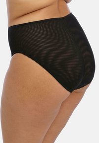 Schwarze hochgeschnittene Panties aus einem transparenten, texturierten Stoff. Mit einem zarten Wellenrand entlang des Taillenbündchens und der Beinausschnitte versehen.