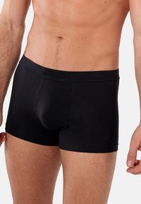 Svarta boxershorts i mjukt tyg med en snug passform, elastisk midja och en framficka. Slät yta med minimala detaljer.