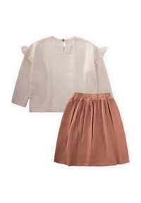 Detský dvojdielny outfit: smotanovo biela, textúrovaná blúzka s dlhými rukávmi a volánikmi na pleciach a ružová, plisovaná sukňa s elastickým pásom.