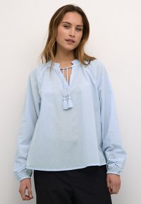 Lichtblauwe blouse met lange mouwen, met een gerimpelde halslijn en strik, met geborduurde accenten op de manchetten en een relaxte pasvorm.