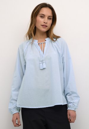 Lichtblauwe blouse met lange mouwen, met een gerimpelde halslijn en strik, met geborduurde accenten op de manchetten en een relaxte pasvorm.
