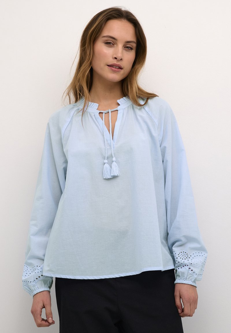 Lichtblauwe blouse met lange mouwen, met een gerimpelde halslijn en strik, met geborduurde accenten op de manchetten en een relaxte pasvorm.