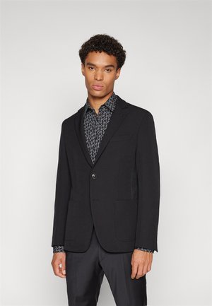 Black blazer with notch lapels and a single button closure, paired with a patterned black and white shirt. Smooth fabric, two front pockets.