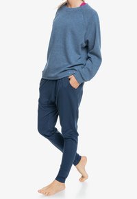 Námořnická modrá strukturovaná mikina s raglánovými rukávy v kombinaci s odpovídajícími jogger kalhotami, které mají boční kapsy a volný střih.