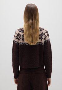 Bruine gebreide trui met een patroon op de schouders in crème en donkerbruin, met een cropped ontwerp en geribbelde mouwen en zoom.