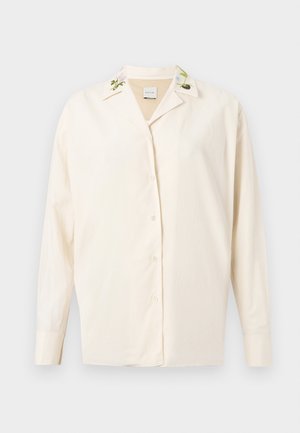 Cream button-up shirt with embroidered floral details on the collar, made from a smooth fabric, featuring long sleeves and a relaxed fit.