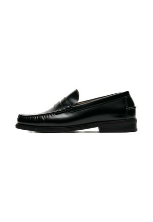 Chaussure penny loafer en cuir noir avec un petit talon et des coutures moc toe, vue de côté sur fond blanc.