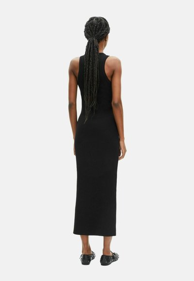 Robe maxi noire à côtes, sans manches, avec une coupe ajustée et un col rond. Portée avec des chaussures noires à enfiler.